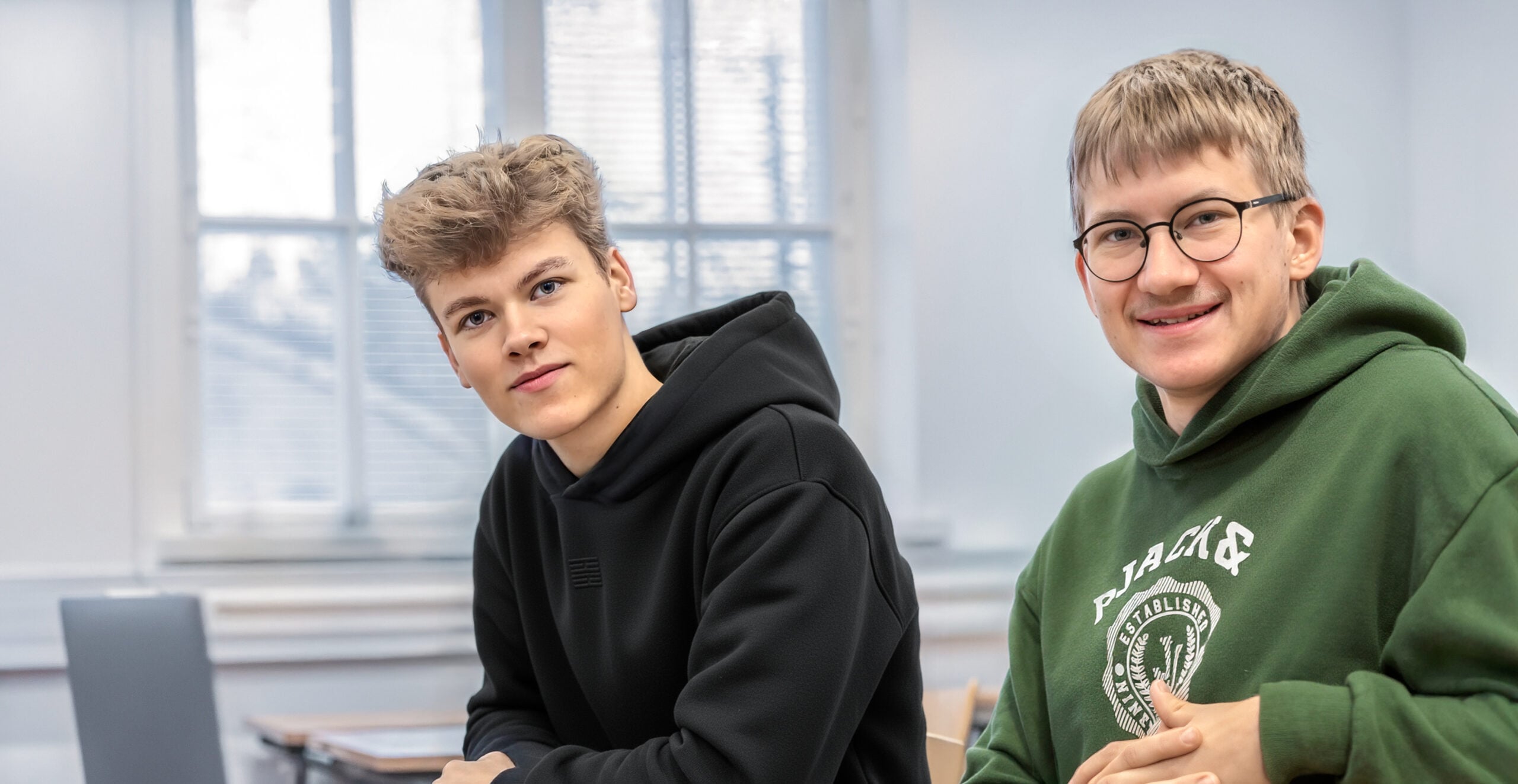 Kaksi nuorta istuu tietokoneen ääressä.